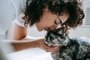 Woman pressing her face and hair against a tabby cat, the kind of contact to avoid after applying minoxidil