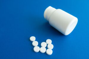 White tablets spilled from a pill bottle onto a table, the hazard oral minoxidil creates for cats